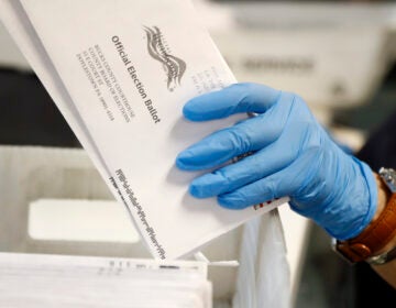 a hand holds mail-in ballots