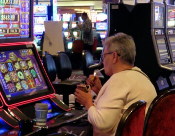 Someone lights a cigarette while playing a slot machine in a casino