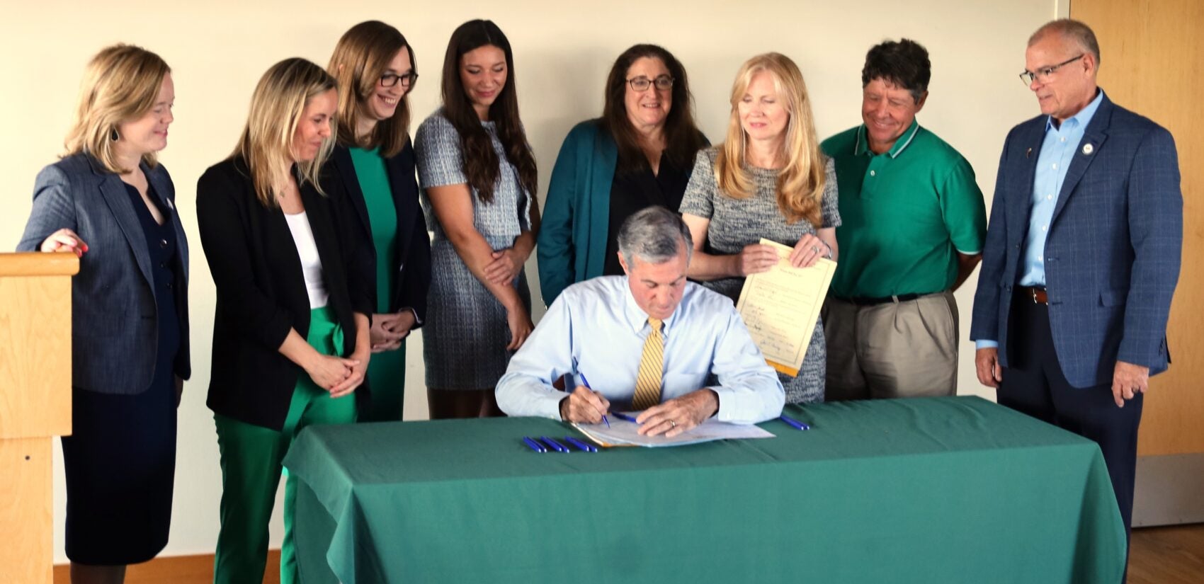 John Carney signs legislation surrounded by others