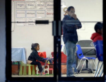 a person stands and a child sits in an immigration support center