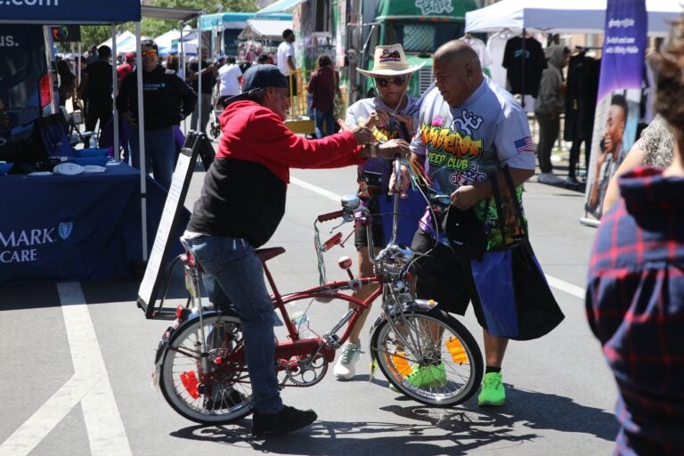 a person on a bike in the street with two other people