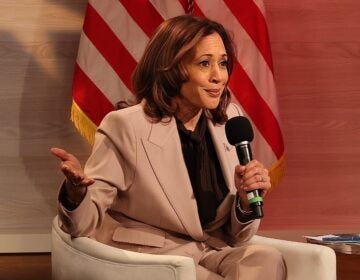 Kamala Harris sitting while holding a microphone