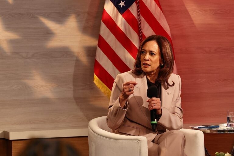 Kamala Harris sitting while holding a microphone