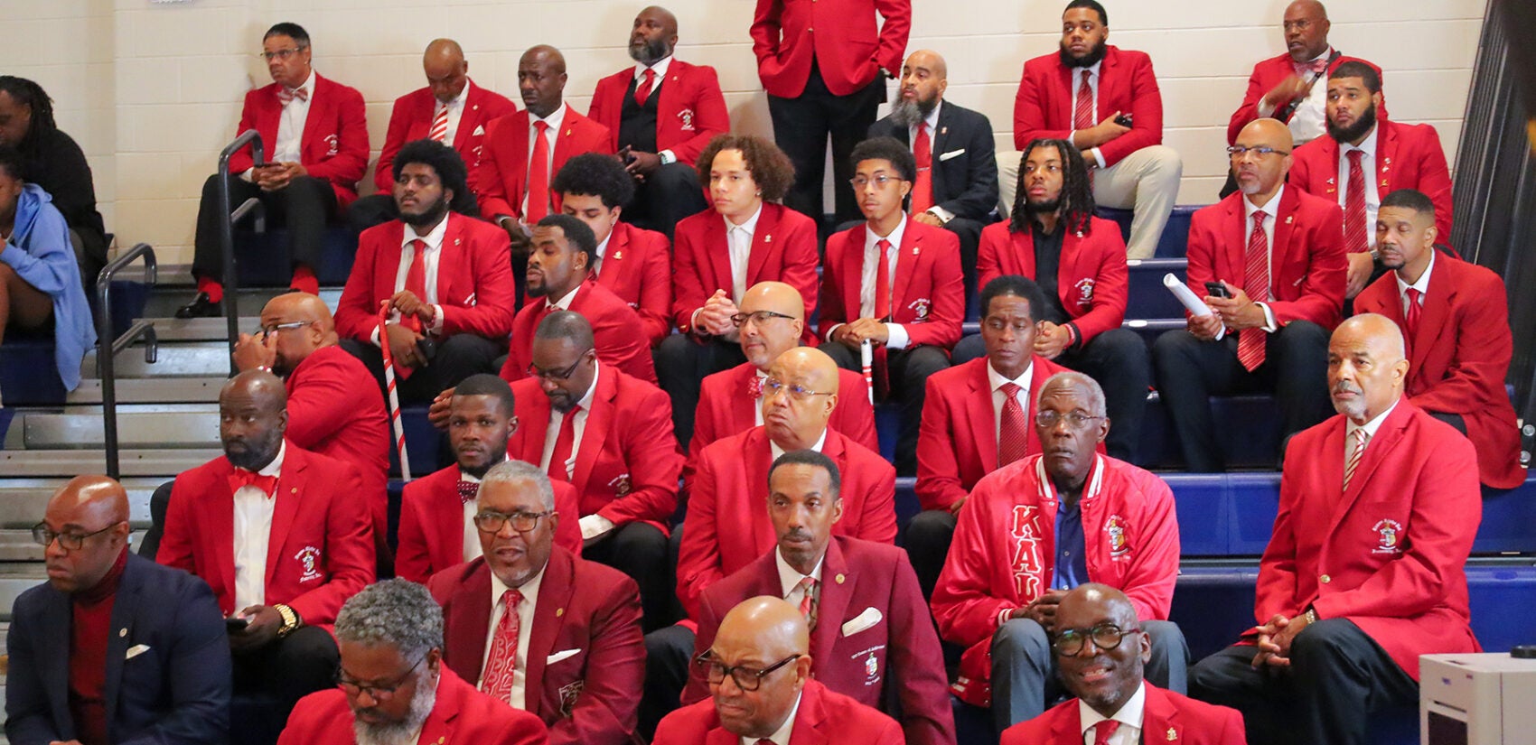 Men sitting in the stands wearing red sports coats