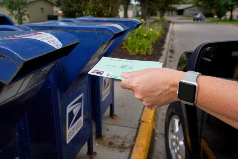 A ballot being dropped off in a mailbox