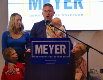 Matt Meyer speaking at a podium standing with his family