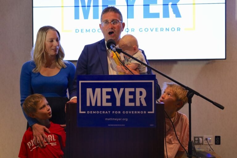 Matt Meyer speaking at a podium standing with his family