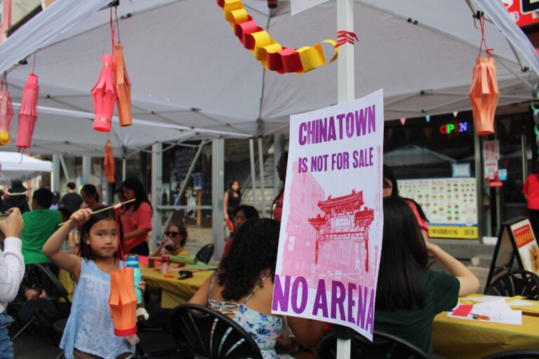 a child plays at a booth next to a sign reading CHINATOWN IS NOT FOR SALE NO ARENA