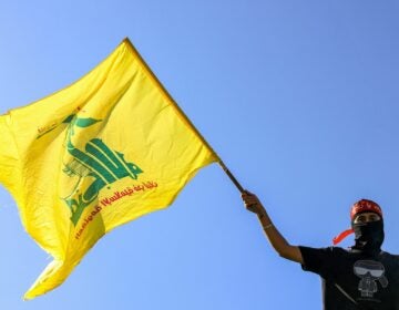 Masked demonstrator waves Hezbollah flag