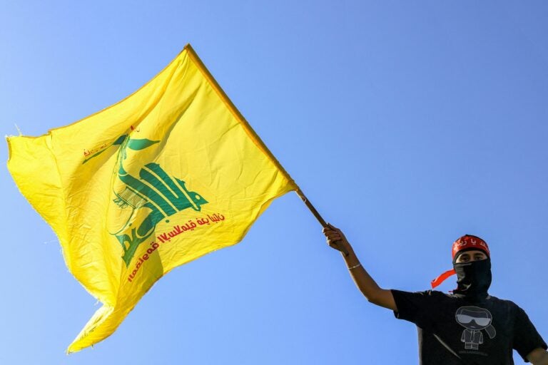 Masked demonstrator waves Hezbollah flag