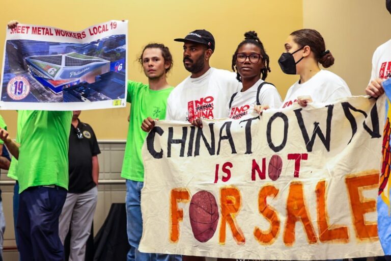 People holding up a sign that says 'Chinatown is not for sale'