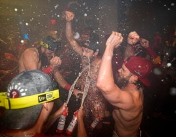 Philadelphia Phillies' Brandon Marsh, from left, Garrett Stubbs and Bryce Harper celebrate after the Phillies won a baseball game against the Chicago Cubs to clinch the NL East title, Monday, Sept. 23, 2024, in Philadelphia.