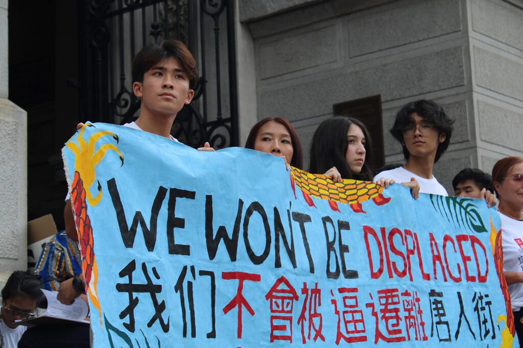 People hold up a banner reading "We won't be displaced"