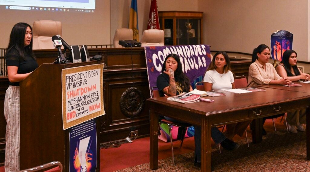 A woman stands at a podium discussing a report about conditions at an immigrant detention center