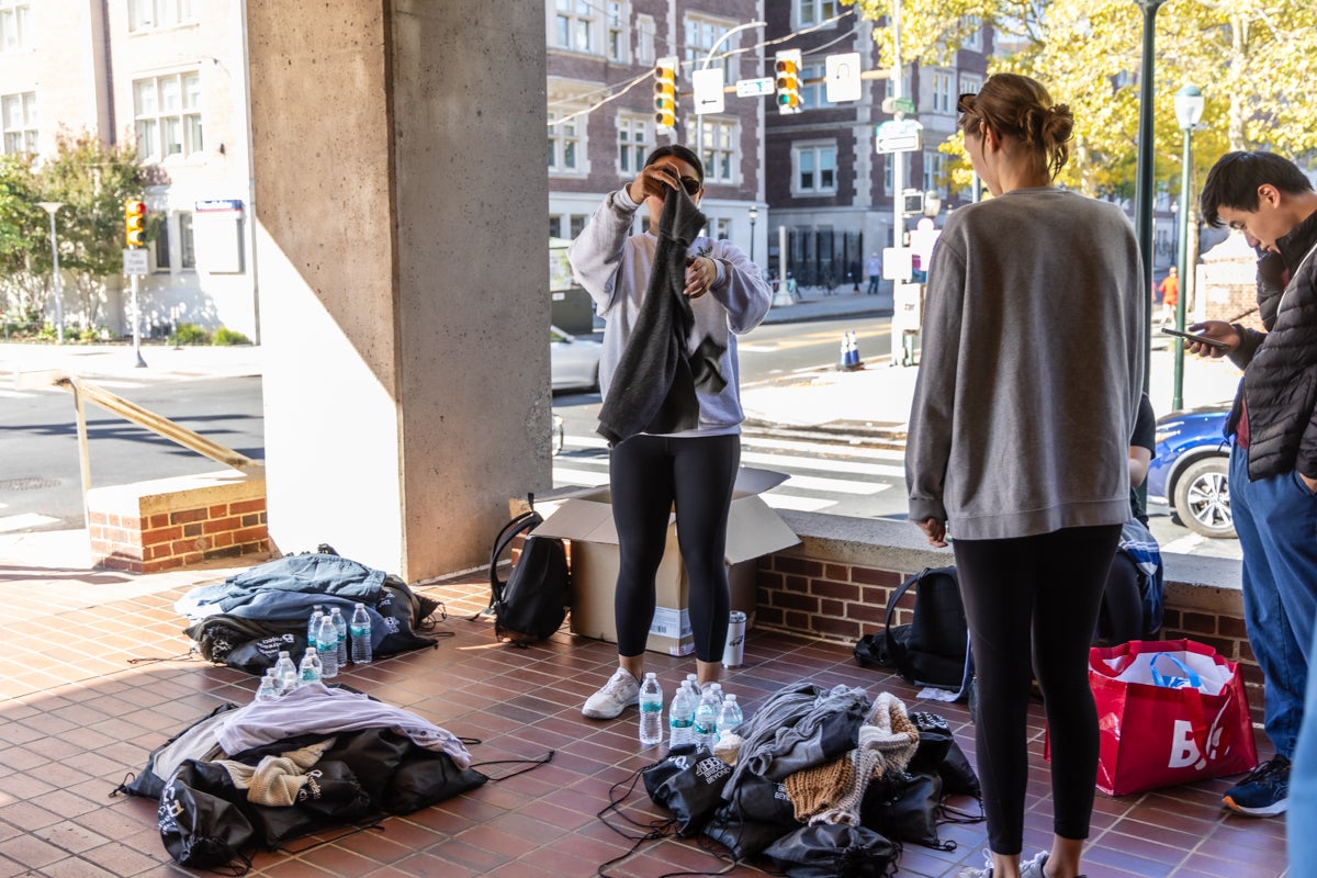 a person folds clothing while two others watch