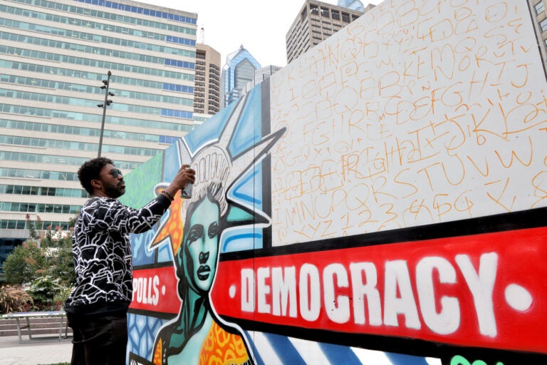 Man spray paints a mural at Love Park