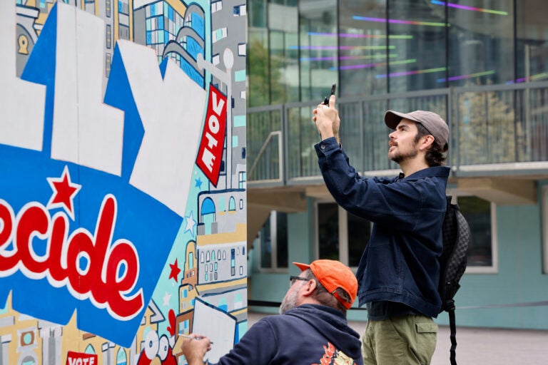 Man takes a photo of a mural at Love Park