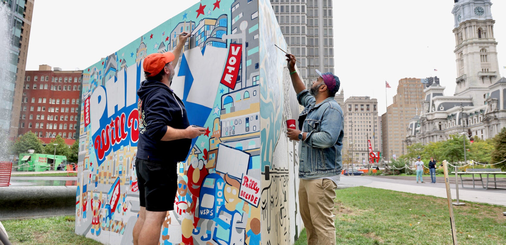 Two men work on a mural in Love Park in Philadelphia