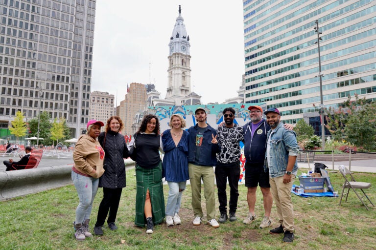 Six artists made murals for this year's ''To The Polls'' exhiibit in Love Park. Pictured are (from left) Serena Saunders, Mural Arts Executive Director Jane Golden, Isabella Akhtarshenas, Nicole Nikolich, curator Conrad Benner, Alloyius McIlwaine, Hawk Krall, and Jeffy Thomas. (Emma Lee/WHYY)