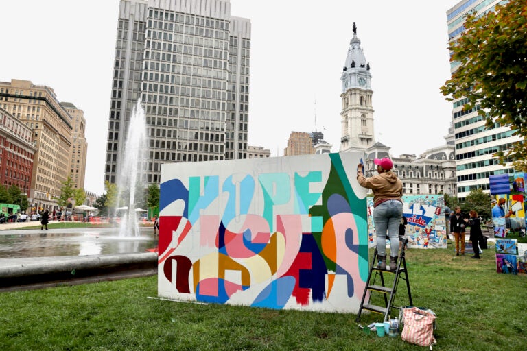 Woman paints a mural at Love Park