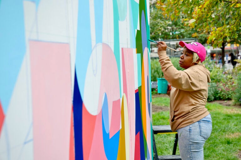 Woman paints a mural at Love Park