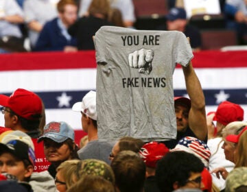 A Trump supporter holds up a T-shirt blasting 