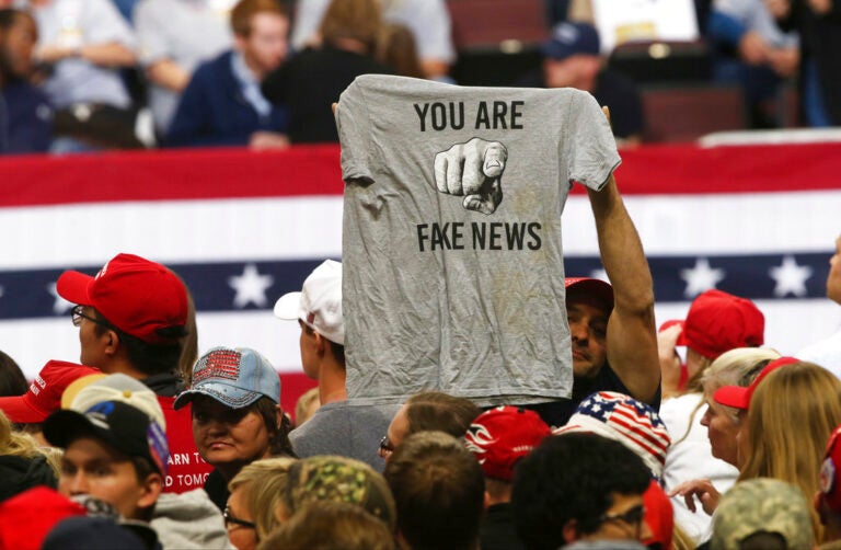 A Trump supporter holds up a T-shirt blasting 