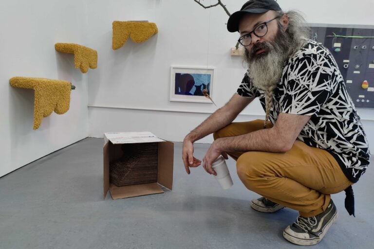 Chriss Hames opens a cat toy made from packaging material inside a package by Heather Mekkelson. (Peter Crimmins/WHYY)