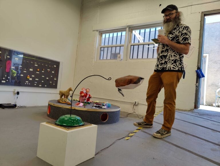 Gallery co-founder Chris Hammes demonstrates a puppet duck spinning on a motorized hook by Ollie Goss. (Peter Crimmins/WHYY)