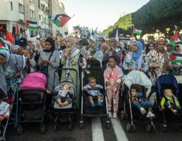 Moroccan women wave flags alongside their children