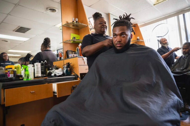 Cherita Evans aka Storm the Barber, with Christian Pounds in her chair at Head Changerz Barber Lounge in Rocky Mount, N.C. on May 23, 2024. (Andrea Ellen Reed/NPR)