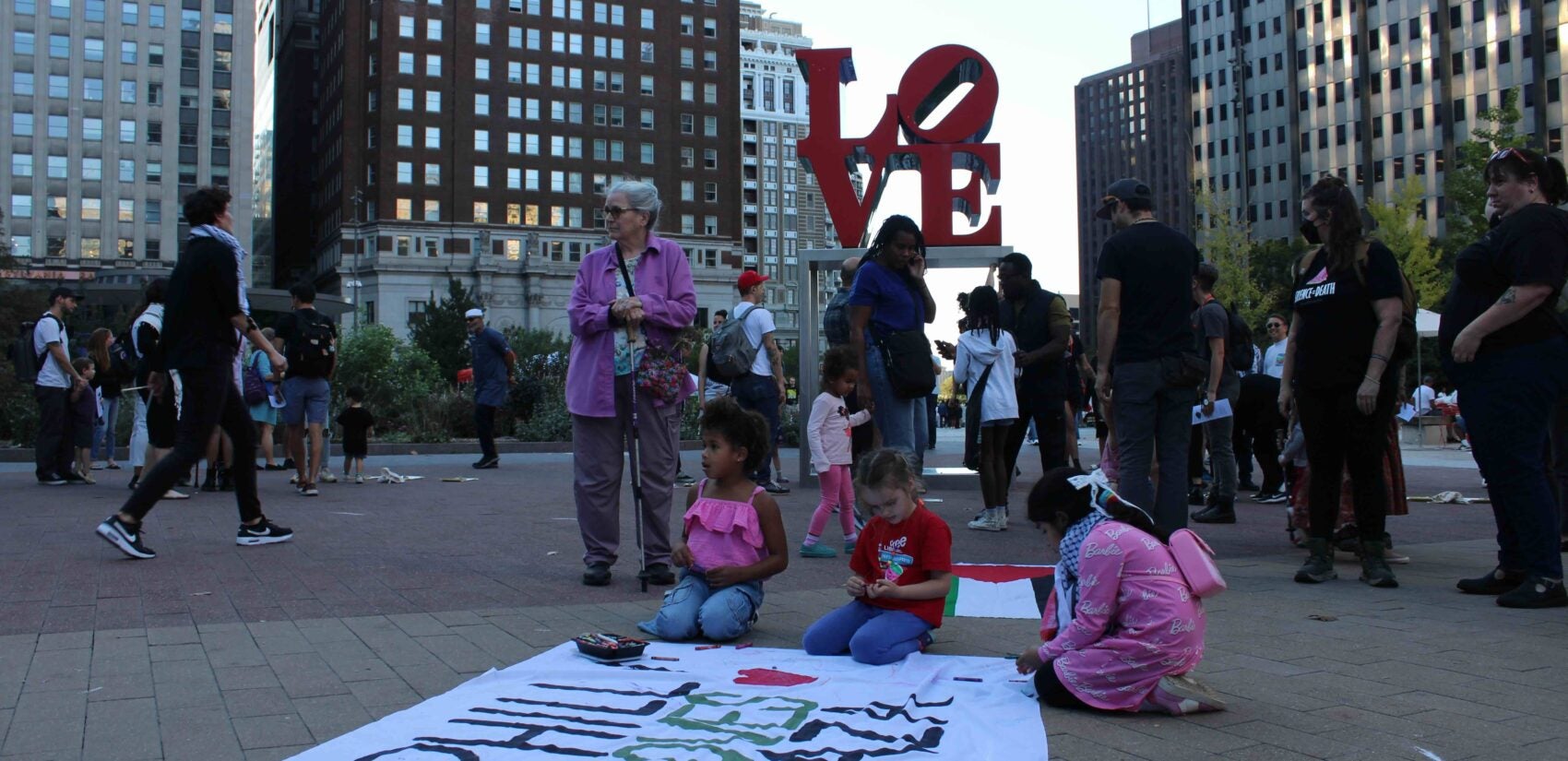 Attendees with a sign at the vigil. (Emily Neil/WHYY)