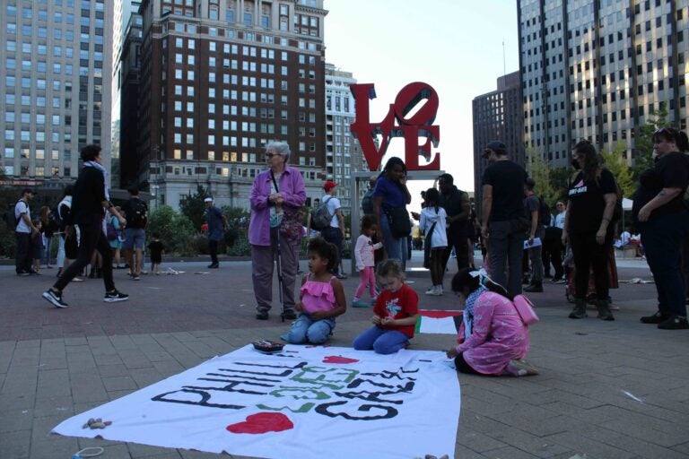 Attendees with a sign at the vigil. (Emily Neil/WHYY)