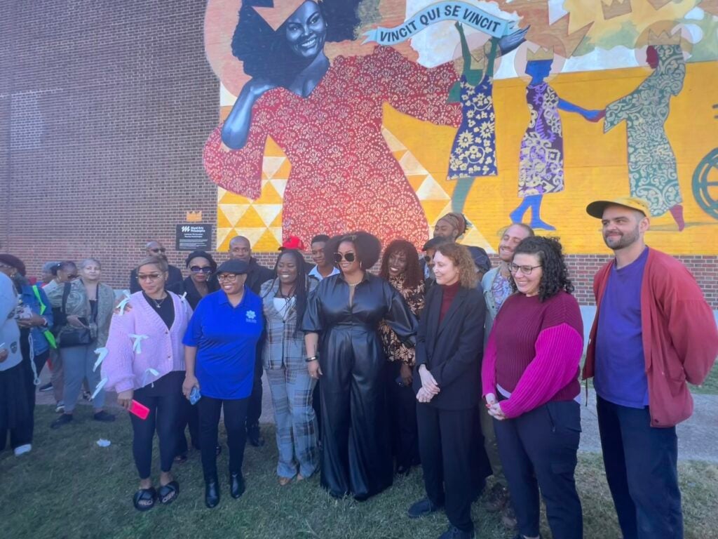 Jill Scott and a group of people posing in front of the mural