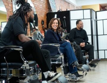 Kamala Harris sits and smiles at a barbershop