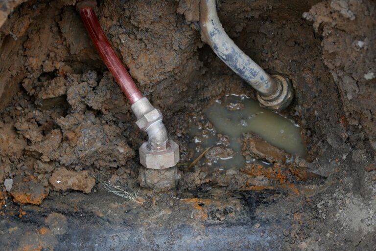 A copper water supply line and a lead pipe in the dirt