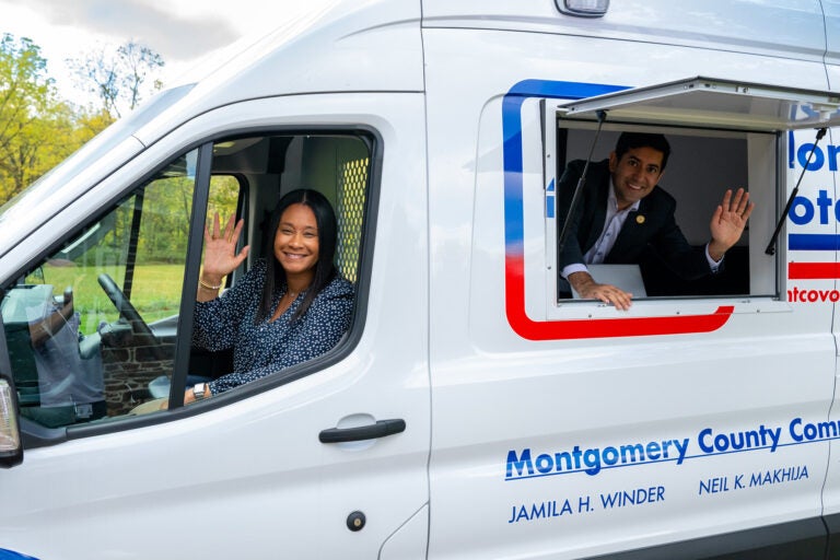 Commissioners Jamila Winder, left, and Neil Makhija, right, pose with Montgomery County's new voter services van.