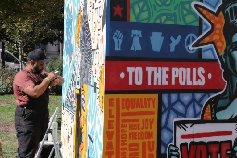 an artist working on a mural that reads TO THE POLLS