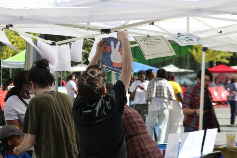 an artist hanging a piece of paper to a canopy