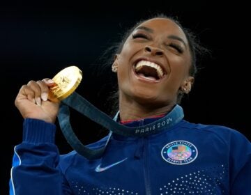 Simone Biles smiles and holds a medal