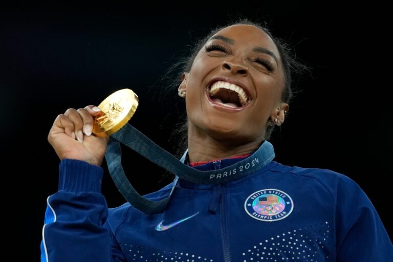 Simone Biles smiles and holds a medal