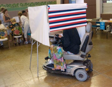 A woman in a motorized wheelchair casts her vote