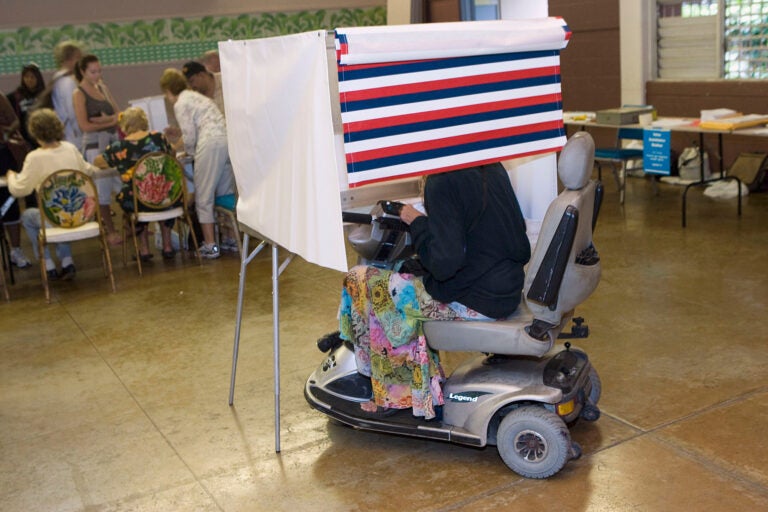 A woman in a motorized wheelchair casts her vote