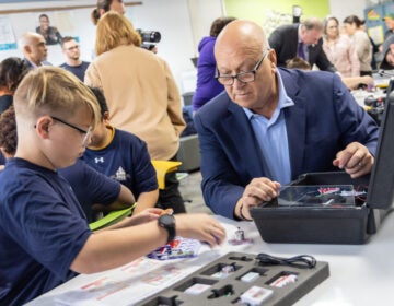 Cal Ripken Jr., baseball Hall of Fame shortstop, helps a Tinicum School student with a STEM activity at the school’s new STEM center, donated by the Cal Ripken Sr. Foundation on November 20, 2024. (Kimberly Paynter/WHYY)