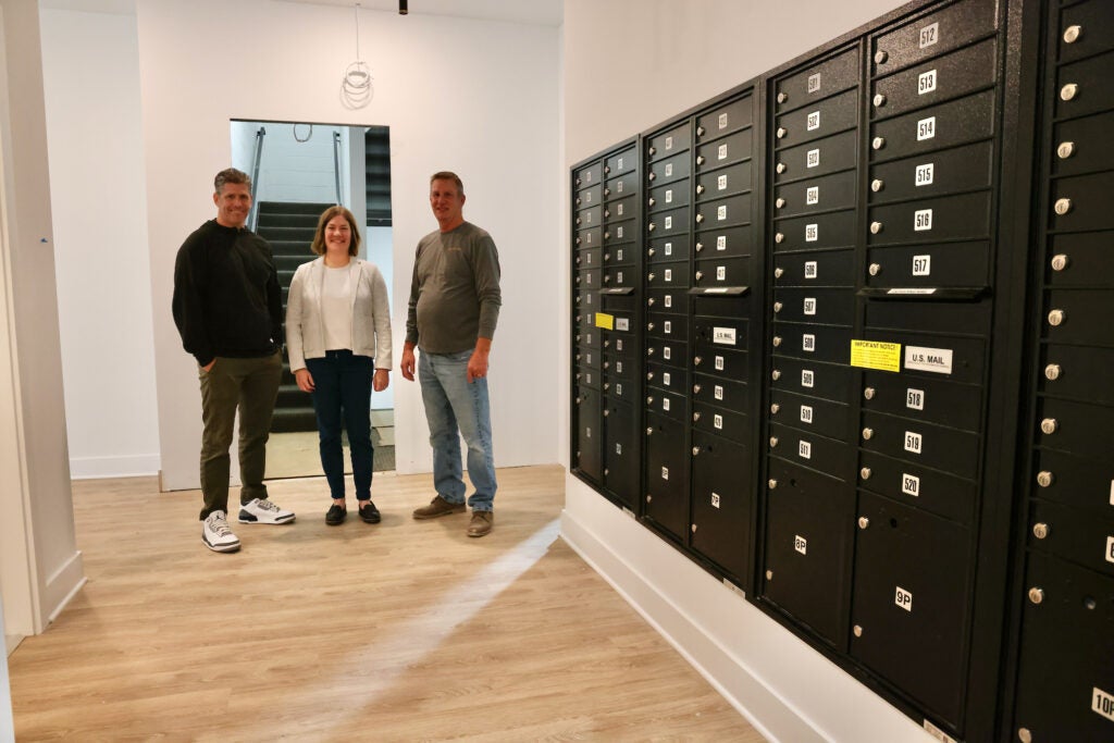 Gary Jonas, Kelli Tomczak and ent Kelli Tomczak and Construction Manager Randy Myers stand by mail boxes in the apartment