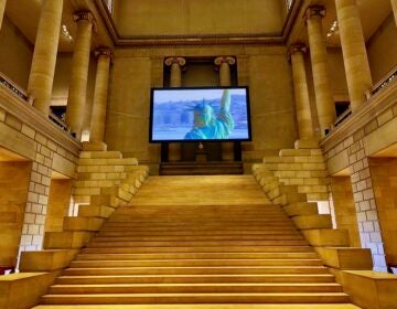 Filmmaker Steve McQueen's ''Static,'' a 7-minute helicopter shot of the Statue of Liberty filmed in 2009 when it reopened for the first time since the 9/11 attacks, occupies the Grand Staircase of the Philadelphia Museum of Art. (Peter Crimmins/WHYY)