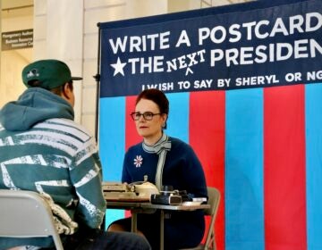 Artist Sheryl Oring listens as Andrew Thomas tells her what he wants to say to the next president of the United States. Oring set up shop at Philadelphia's Central Library and typed the postcard on a vintage typewriter.