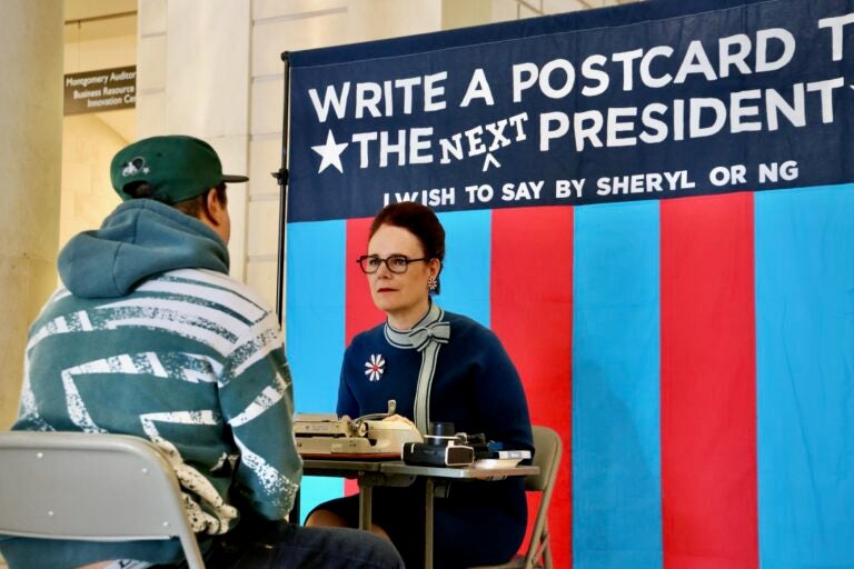 Artist Sheryl Oring listens as Andrew Thomas tells her what he wants to say to the next president of the United States. Oring set up shop at Philadelphia's Central Library and typed the postcard on a vintage typewriter.