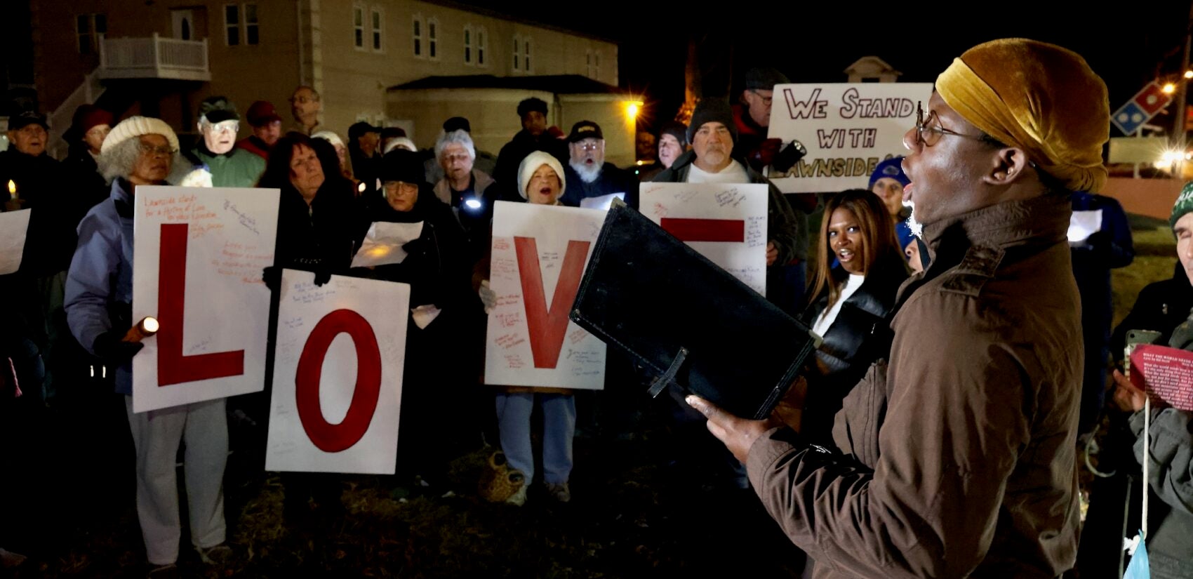 Lawnside resident Charles McNeil sings, and residents hold four signs reading LOVE