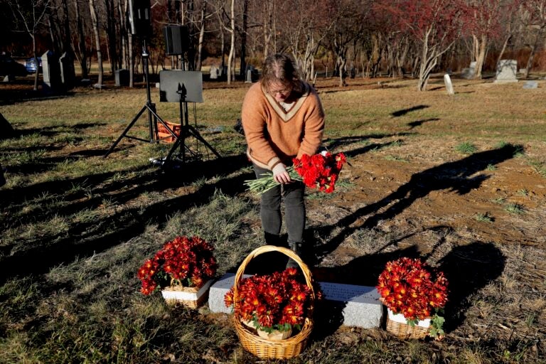 Jennifer O'Donnell of the Friends of Mount Moriah Cemetery lays a bouquet at the reburial site for the remains of nearly 500 people unearthed from a former burial in Old City, Philadelphia. (Emma Lee/WHYY)